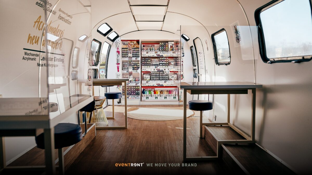 The interior of the Edding AirStreamer with table and seats ready for consultations with the product wall ready for use.